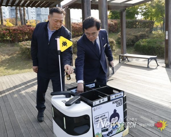 진교훈 서울 강서구청장(오른쪽)이 마곡하늬공원에서 열린 ‘AI 기반 자율주행 로봇서비스 실증 시연회’에서 빈 캔을 수거함에 넣고 있다.