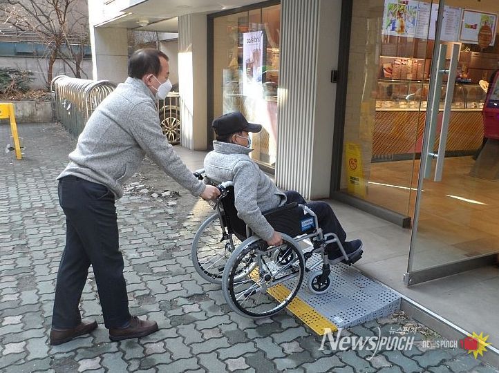 ‘맞춤형 경사로’를 설치한 가게로 휠체어 이용 주민이 이동하고 있는 모습